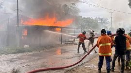 Petugas berupaya memadamkan api pada bangunan yang dibakar oleh massa. (Dok. Merdeka.com)