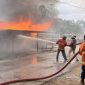 Petugas berupaya memadamkan api pada bangunan yang dibakar oleh massa. (Dok. Merdeka.com)